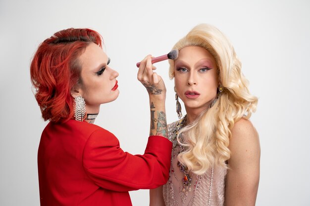 Medium shot drag queens putting on makeup