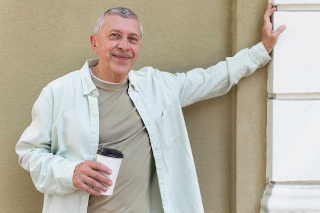 Free photo medium shot elderly holding coffee cup