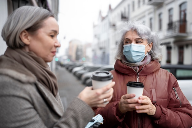 Donne anziane del colpo medio con le tazze di caffè