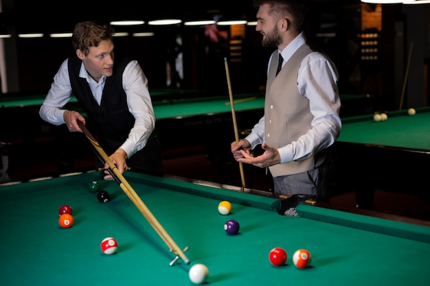 Medium shot elegant guys playing billiard