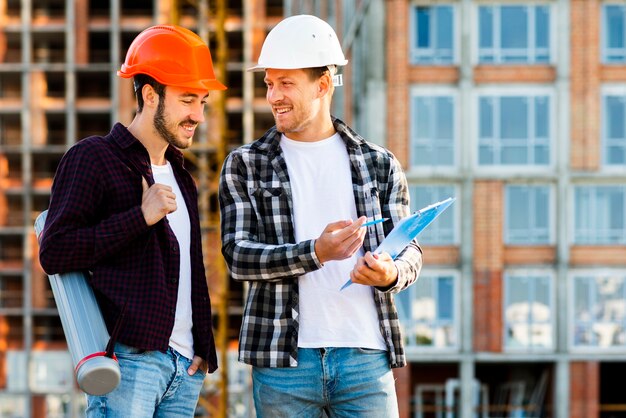 Medium shot of engineer and architect  looking at clipboard