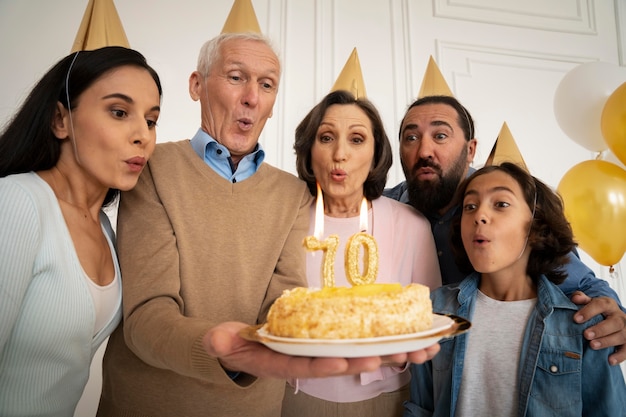 Foto gratuita famiglia a ripresa media che festeggia con la torta