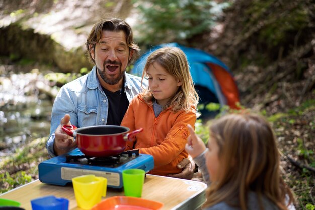 Medium shot family cooking in nature