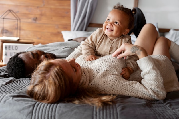 Medium shot family laying with kid on bed