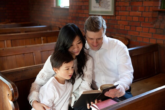 教会で聖書を読んでいるミディアムショットの家族