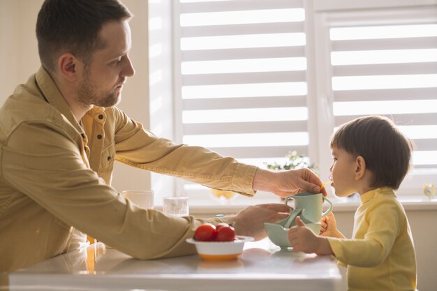 Medium shot family taking breakfast in the kitchen