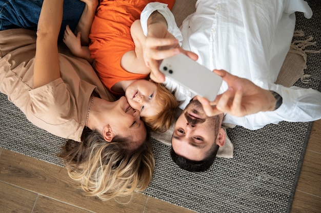Medium shot family taking selfie with smartphone