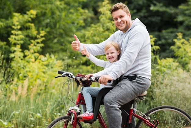 Medium shot father and daughter on bike