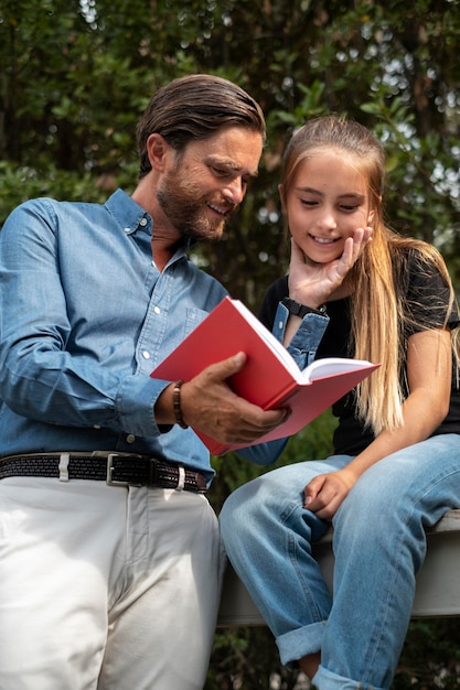 Средний план отец и девочка читают книгу