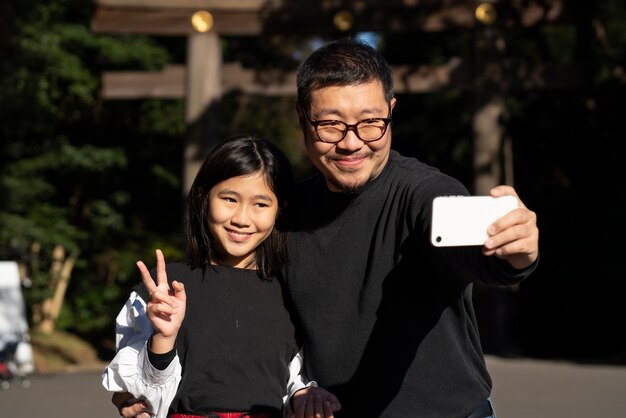 Medium shot father and girl taking selfie