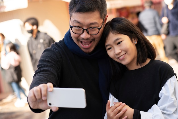 Medium shot father and girl taking selfie