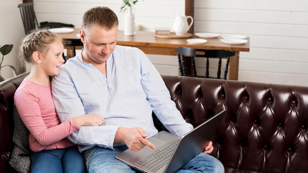 Medium shot father and girl with laptop