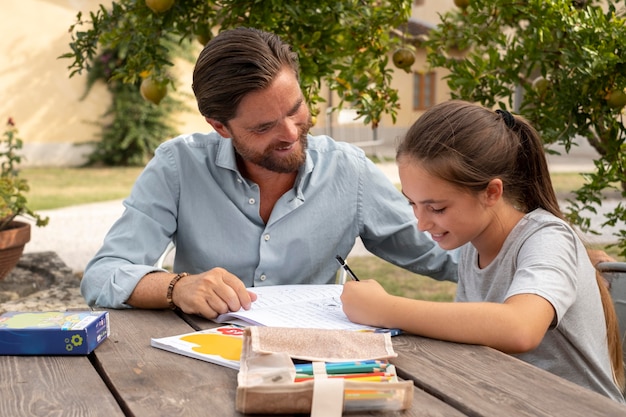 Foto gratuita padre di tiro medio che aiuta la ragazza con i compiti