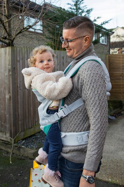 Medium shot father holding baby in carrier