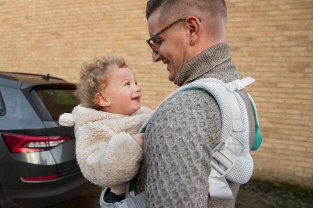 Medium shot father holding baby in carrier