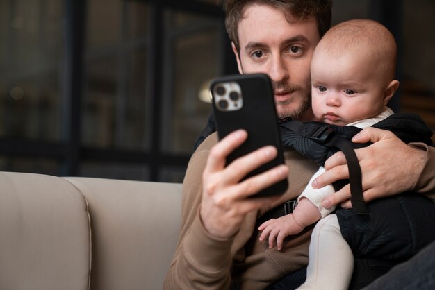 Foto gratuita padre del colpo medio che tiene bambino e telefono