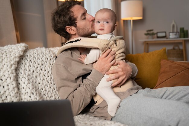 Medium shot father holding cute baby in carrier