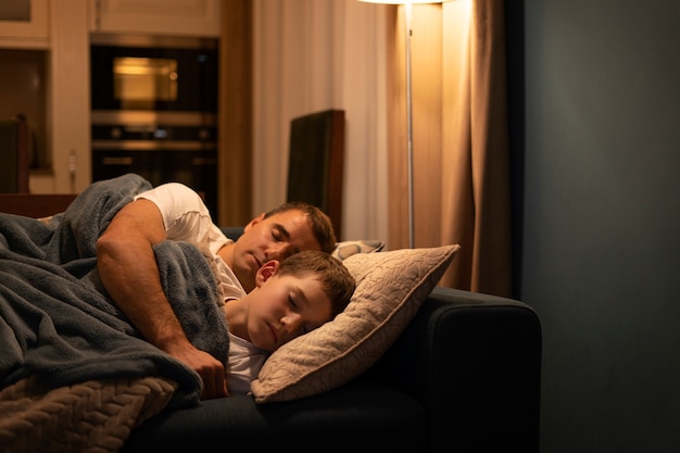 Средний снимок отца и ребенка, спящих на диване