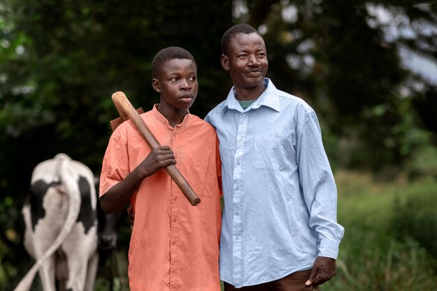 Medium shot father and kid with cow outdoors