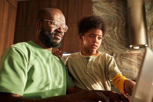 Medium shot father and kid with laptop