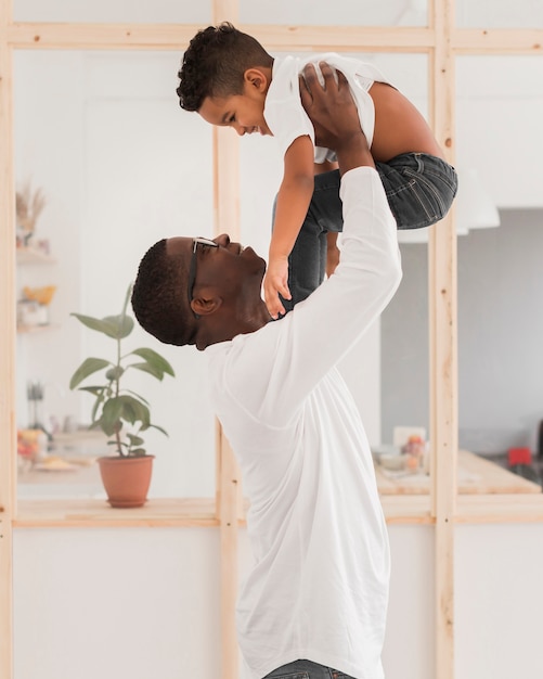 Medium shot father playing with his son indoors