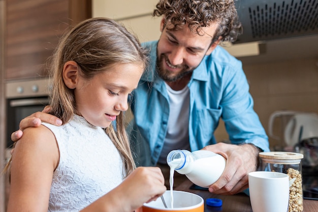 Medium shot of father pouring milk for his daughter