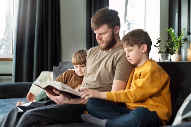 Medium shot father reading bible to kids
