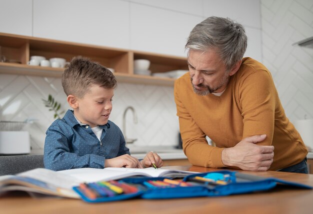 Medium shot father watching kid do homework