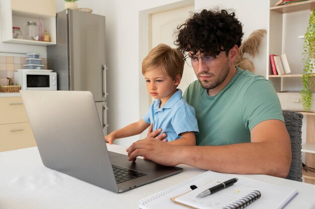 Padre del tiro medio che lavora al computer portatile