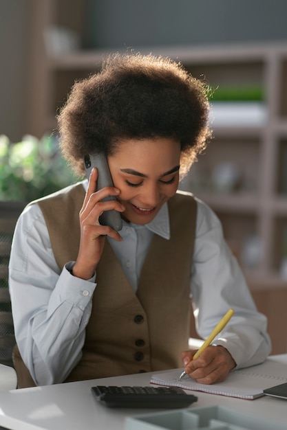 Foto gratuita economista femminile del colpo medio che tiene smartphone