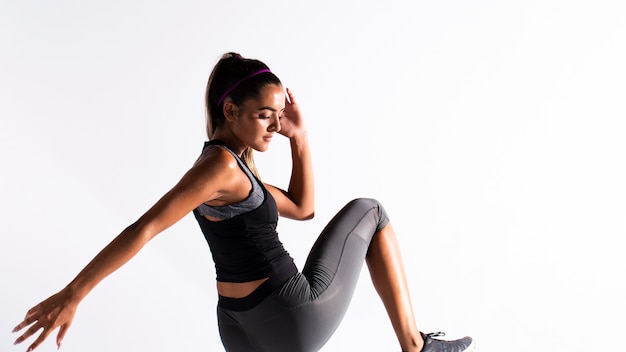 Medium shot fit girl in gym suit exercising indoors