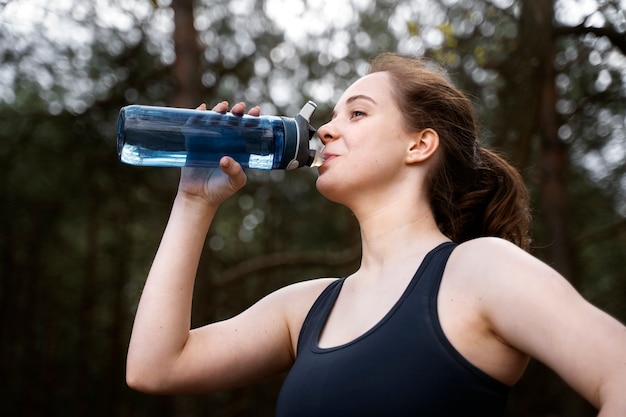Женщина среднего роста пьет воду