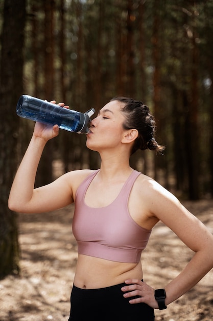 Free photo medium shot fit woman drinking water