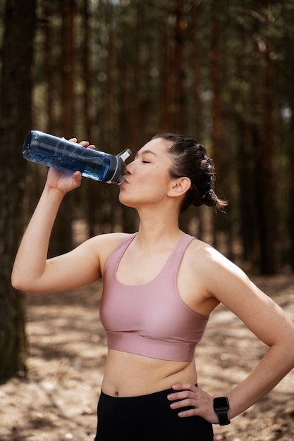 Medium shot fit woman drinking water