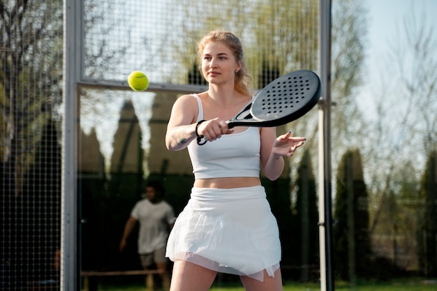 Женщина среднего роста играет в паддл-теннис