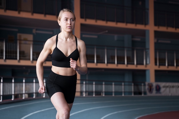 Medium shot fit woman running at gym