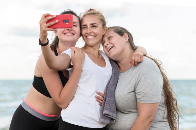 Medium shot fitness friends taking selfie