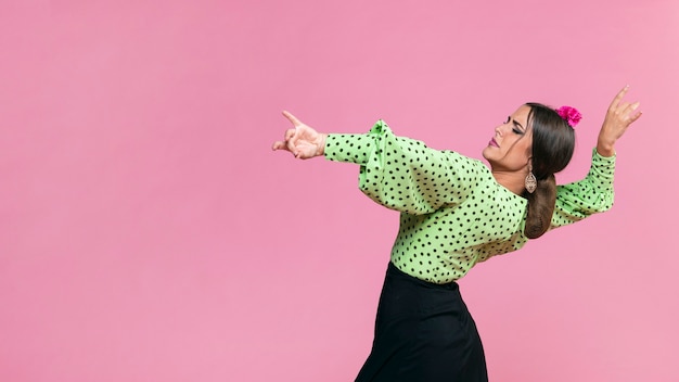 Foto gratuita flamenca del colpo medio che esegue floreo su fondo rosa