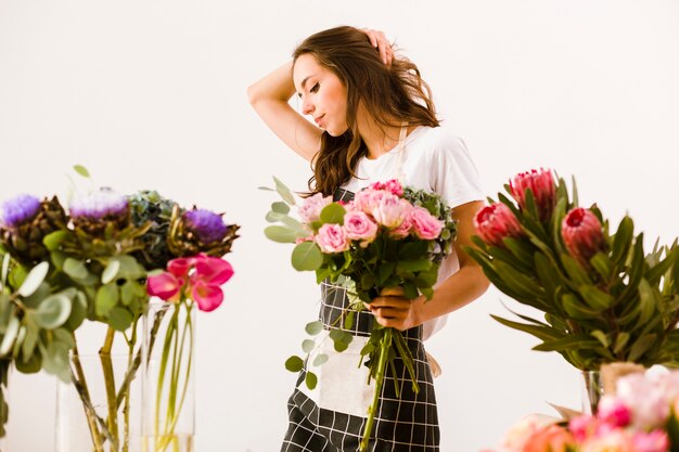 Medium shot florist posing with bouquet indoors
