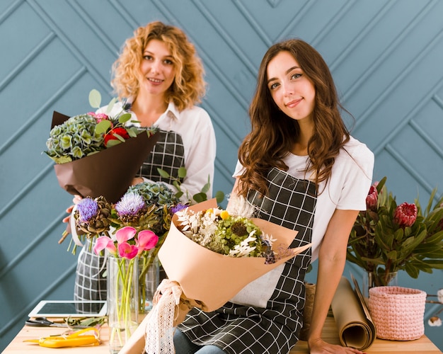 Foto gratuita fioristi del colpo medio che posano con i fiori