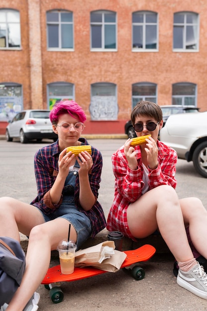 Free photo medium shot friends eating corn