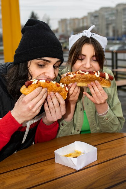 Medium shot friends eating fast food in a funny way