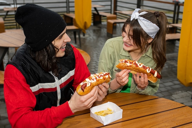 Medium shot friends eating fast food in a funny way