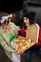 Free photo medium shot friends eating fast food in a funny way