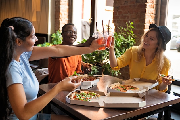 Free photo medium shot friends eating pizza