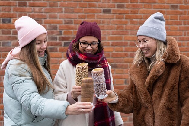 Medium shot friends holding chimney cake