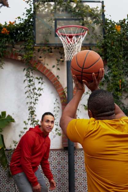 Medium shot friends playing basketball outdoors