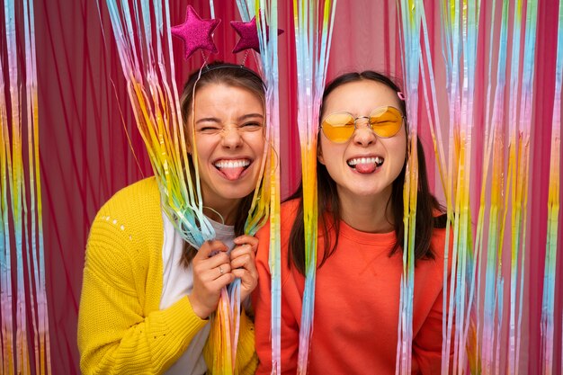 Medium shot friends posing in photo booth