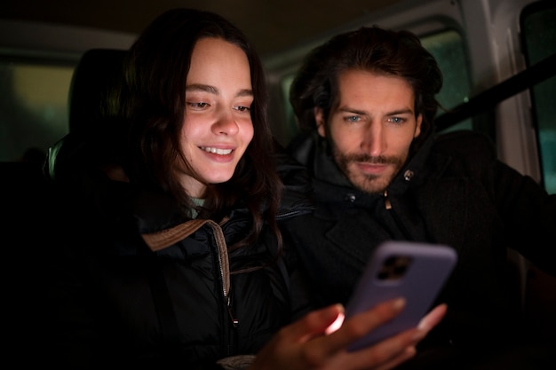 Бесплатное фото Друзья среднего плана читают сообщения мобильного телефона в машине