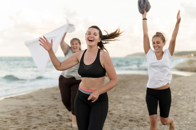 Medium shot friends running on beach